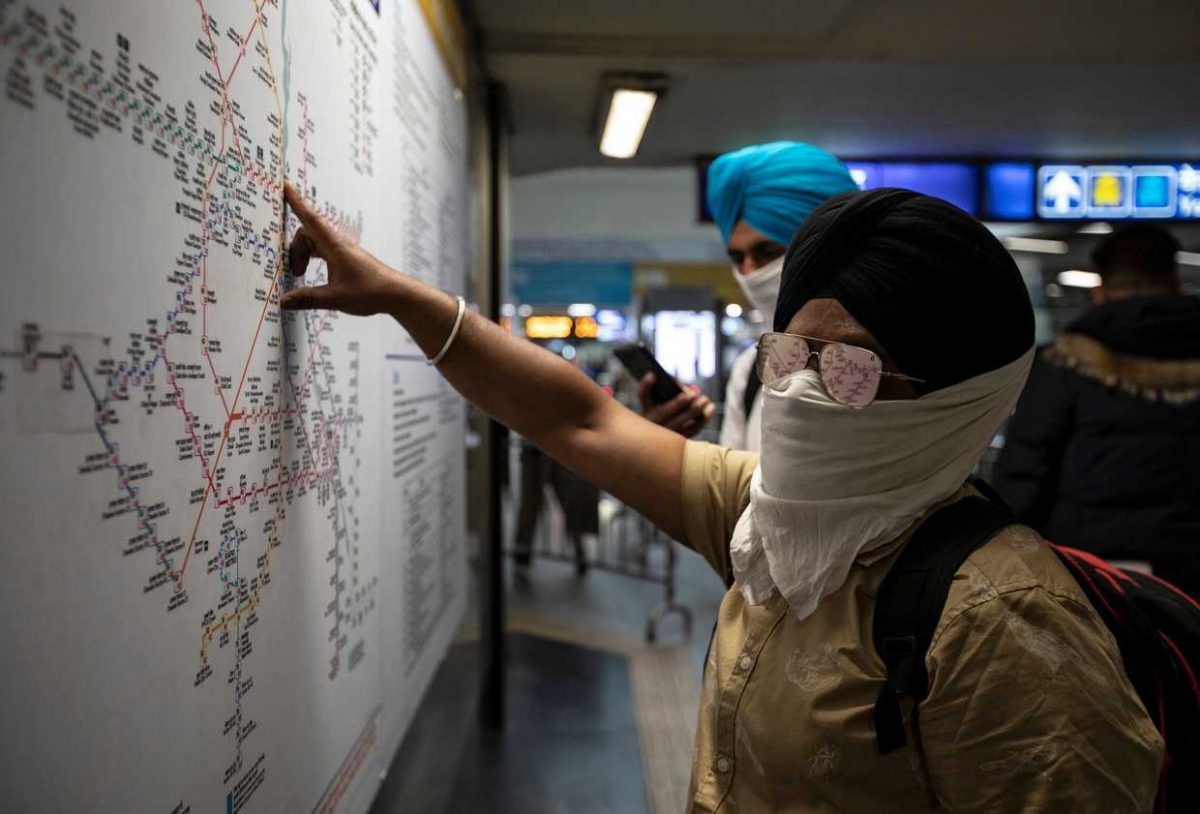 Commuters wearing handkerchiefs as masks look at a metro train map at a station, amid coronavirus disease fears, in New Delhi, India