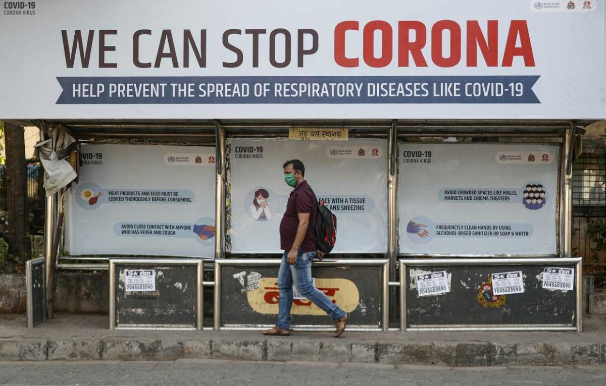 A man wearing a protective mask walks past a bus stop displaying preventive measures against the coronavirus in Mumbai, India, March 18, 2020